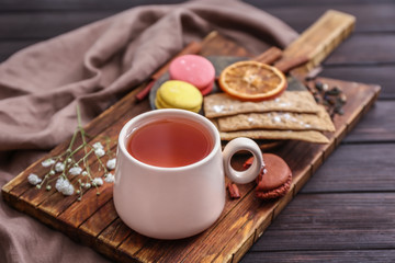Cup of hot tea with sweets on wooden table