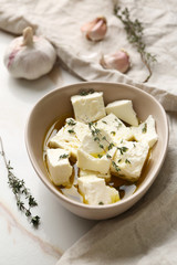 Plate with tasty feta cheese, thyme and olive oil on light background