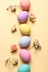 Easter eggs with flowers on color background