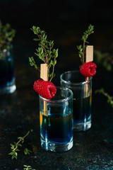Colorful shots on a dark background. Cocktails in the bar with raspberries and thyme.