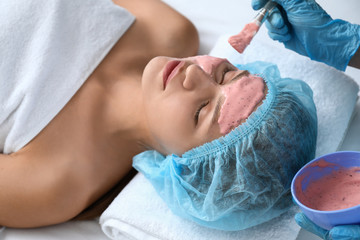 Obraz na płótnie Canvas Cosmetologist applying alginate mask on young woman's face in beauty salon