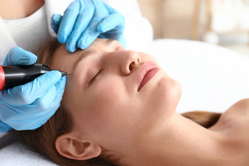 Fototapeta na wymiar Young woman undergoing procedure of permanent makeup in beauty salon