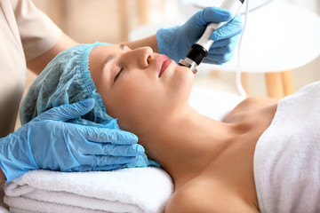 Naklejka premium Young woman undergoing procedure of rf lifting in beauty salon