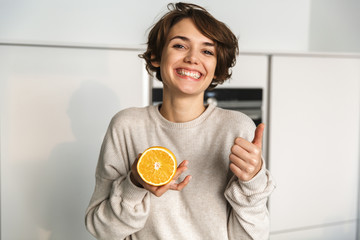 Happy woman showing orange fruit