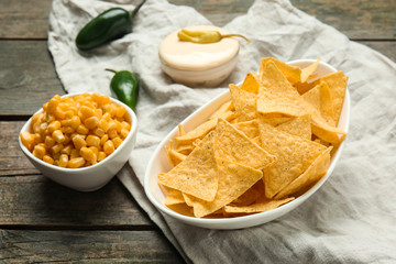 Plate with tasty nachos and corn on table