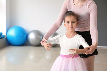 Little ballerina training with coach in dance studio