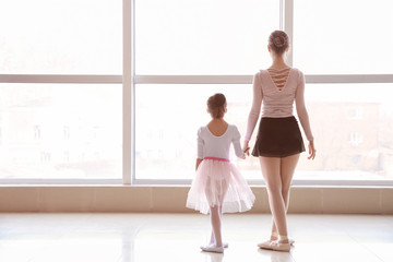 Little ballerina training with coach in dance studio