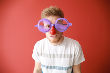 Funny man with party decor for April Fools' Day on color background