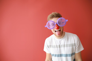 Funny man with party decor for April Fools' Day on color background