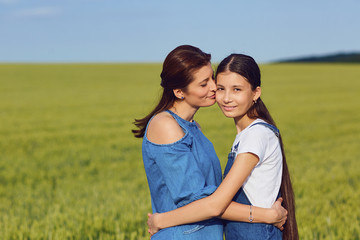 Mother and daughter embrace in a field.