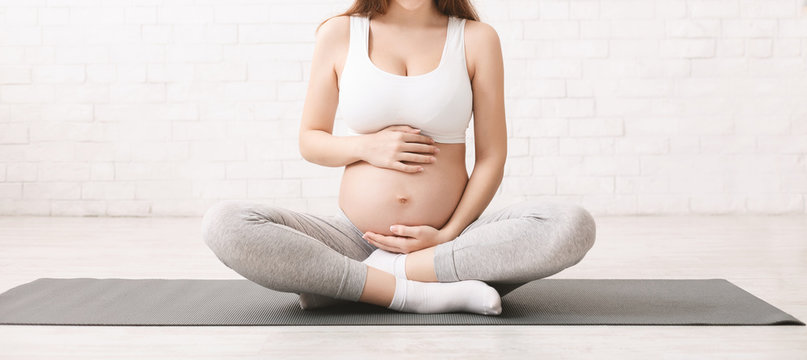 Pregnant woman meditating in lotus position at home