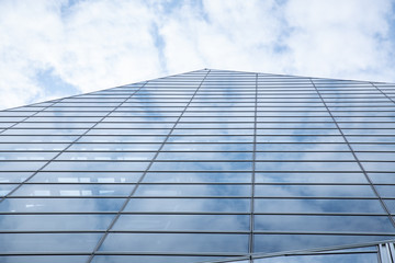 Obraz premium Cloud and sky reflected in the blue glass windows of building.