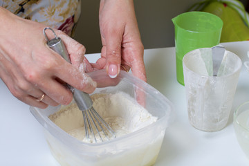 Cooking the pie with mascarpone cream. Woman kneads dough in container.
