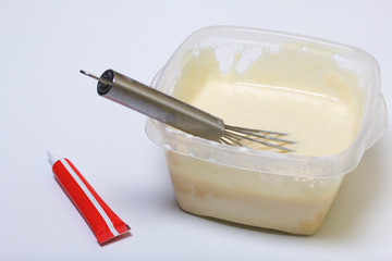 Cooking the pie with mascarpone cream. A whisk for mixing is in the container with the dough. Next is a food dye in a tube.