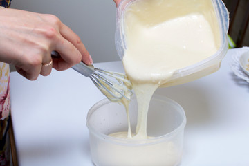 Cooking the pie with mascarpone cream. A woman divides the dough into two containers.