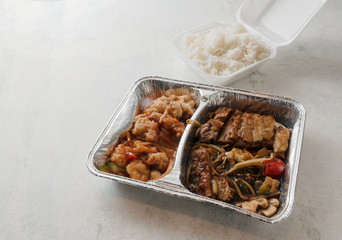 Asian fast food from delivery service in a foil container and rice in a foam box on a bright background, high angle view from above, copy space