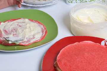 Cooking the pie with mascarpone cream. A woman lubricates the mascarpone and condensed milk cakes.