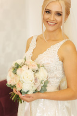 Portrait of gorgeous bride at home. Charming woman with bouquet. Morning of beautiful bride. Wedding day