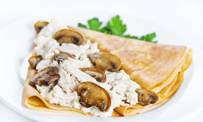 Thin delicious pancake with mushrooms and meat on white