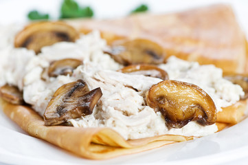 Thin delicious pancake with mushrooms and meat on white