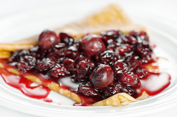 Thin delicious pancake with berry jam on white