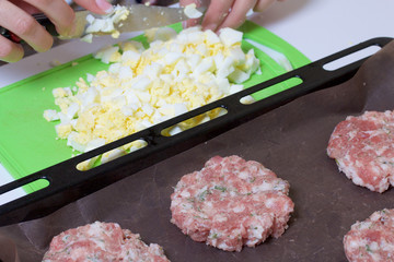 Woman crushes boiled chicken eggs. Minced meat steaks with potatoes, eggs and cheese. Cooking steps and ingredients.