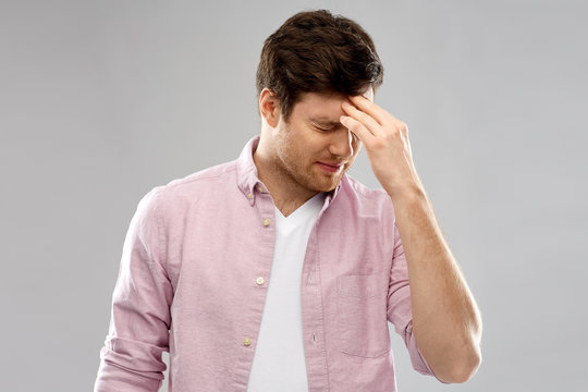 mind, health problem and stress concept - unhappy indian man suffering from headache over grey background