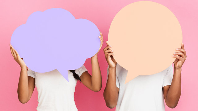Couple holding blank speech bubbles, pink background