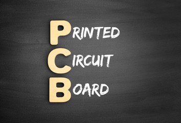 Wooden alphabets building the word PCB - Printed Circuit Board acronym on blackboard