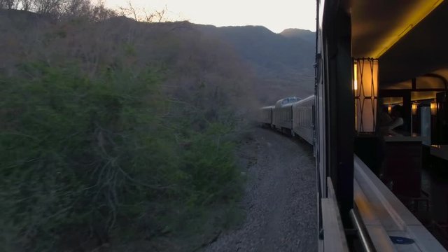 The view from the window in a moving train through arid scenery at sunset