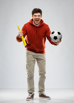 sport, leisure games and people - happy man or football fan in red hoodie with soccer ball and vuvuzela over grey background