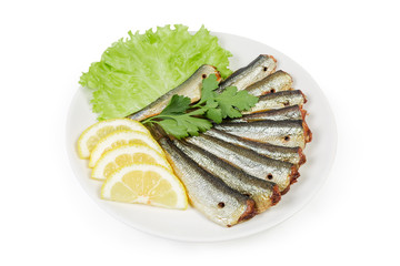 Smoked sprats with lemon and greens on a white saucer