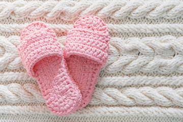 Fototapeta na wymiar Womens pink Slippers on a white knitted wool carpet