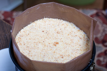 Cooking a cake of biscuit crumbs and milk jelly. On the surface of the table are the ingredients and cooking utensils.