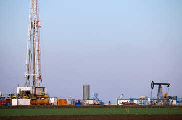 Oil and gas drilling rig and pump jack in oilfield mining industry