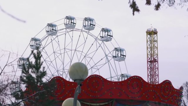 Motionless ferris wheel in the amusement park on grey sky background. Stock. Amusement park in autumn without people.