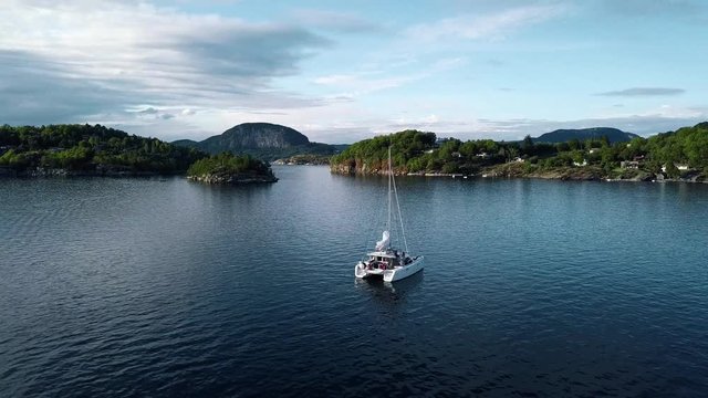 Catamaran cruising on the norwegian fjord in beautiful landscape.
