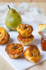 Delicious home made breakfast: sweet cupcakes with pears. Served with honey in a glass jar and walnuts on a white board.