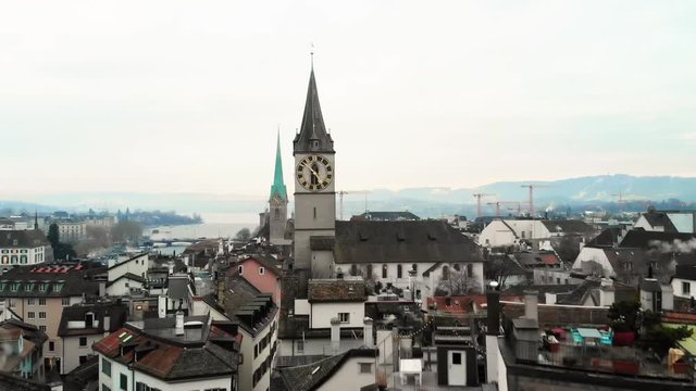 Aerial view of Zurich rooftops and a Church of St. Peter with a clock tower The city of Zurich, a global center for banking and finance, lies at the north end of Lake Zurich in northern Switzerland.