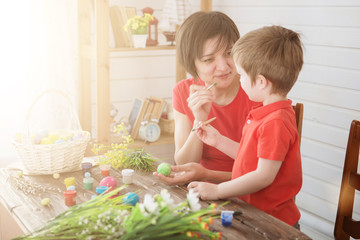 Happy family Mom and children son paint easter eggs with colors. Preparation for holiday.