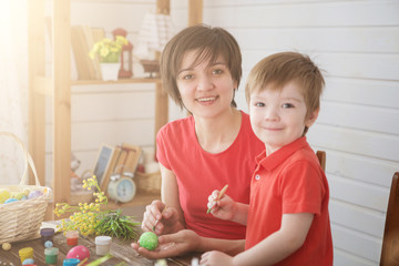 Happy family Mom and children son paint easter eggs with colors. Preparation for holiday.