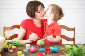 Easter concept. Happy mother and her cute child getting ready for Easter by painting the eggs. Happy family Mom and children son paint easter eggs with colors. Preparation for holiday.