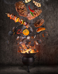 Kettle grill with hot briquettes, cast iron grate and tasty meats flying in the air. Freeze motion...