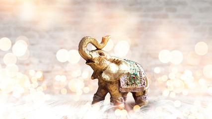 Golden elephant on a wooden table. room, light effect. Beautiful statuette of an elephant on the background.