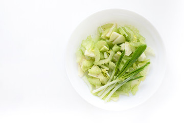 Spring vitamin salad with celery apple and greens in a white plate, top view