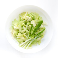Spring salad with celery apple and greens in a white plate, top view, diet concept