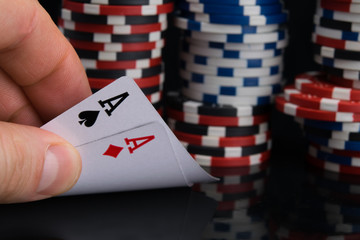 the man's hand checks the cards for playing in the casino, opens two aces, against the background of a large bet