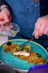 Chef decorates the halibut stewed in mango sauce. Master class in the kitchen. The process of cooking. Step by step. Tutorial. Close-up