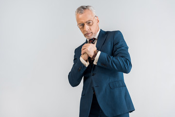 mature businessman in suit standing with clenched hands isolated on grey