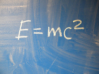 Mathematical formula e=mc2 squared written on a blue, relatively dirty chalkboard by chalk.